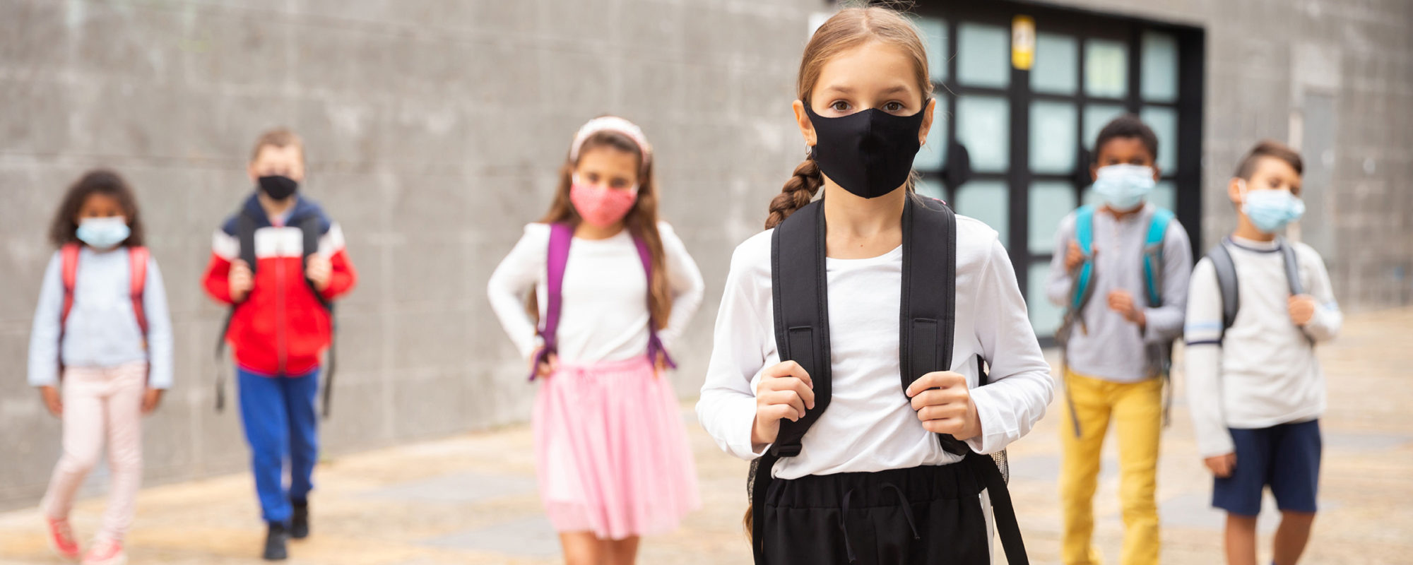 Kinder gehen mit Maske zur Schule, um sich gegen eine Durchseuchung mit dem Coronavirus zu schützen